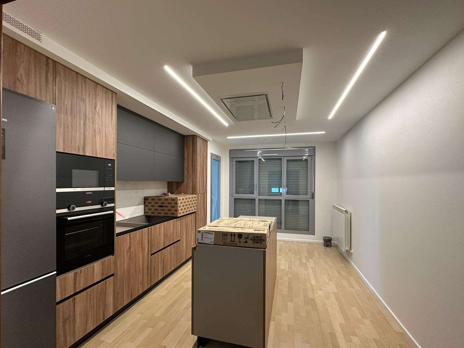 Helle Küche mit Parkettboden und Deckenleuchten nach der Renovation